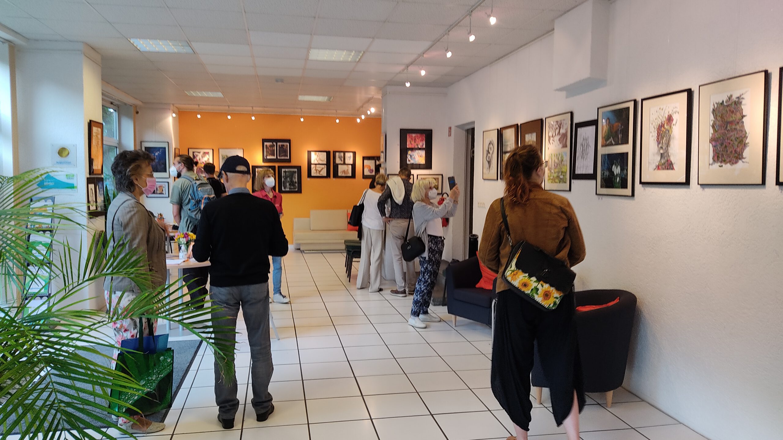 Menschen in der Galerie sehen sich Bilder an.
