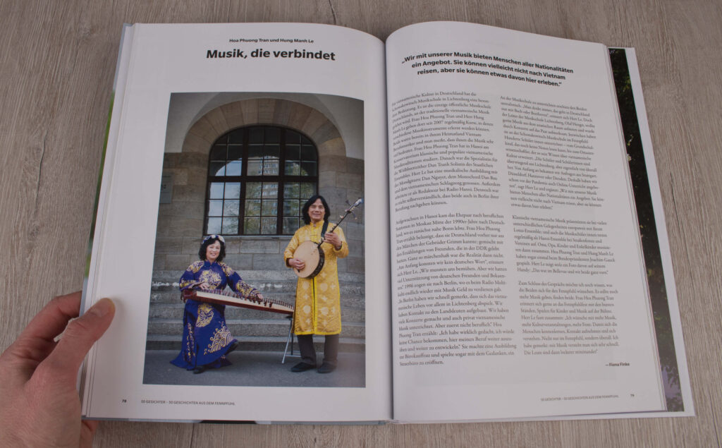 Ein aufgeschlagenes Buch, rechts das Foto von zwei Musiker:innen in gelb-lila  und asiatisch aussehender Tracht