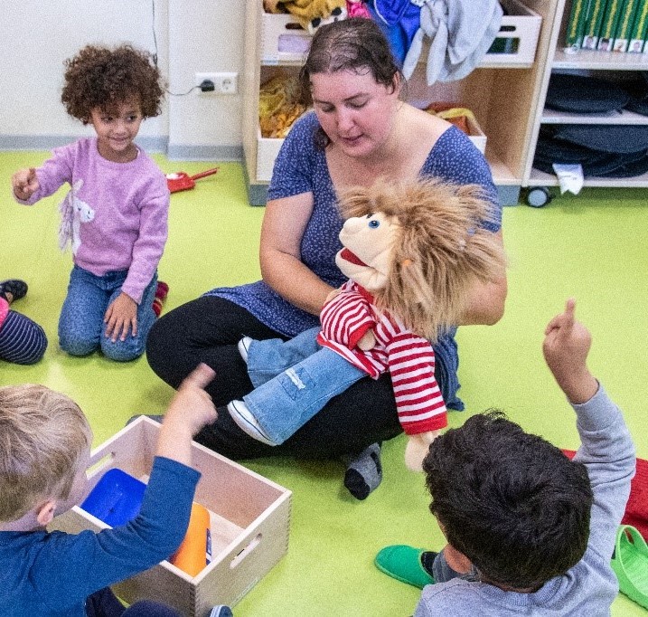 Kinder auf einer Grünen Matte spielen mir einer erwachsenen Frau