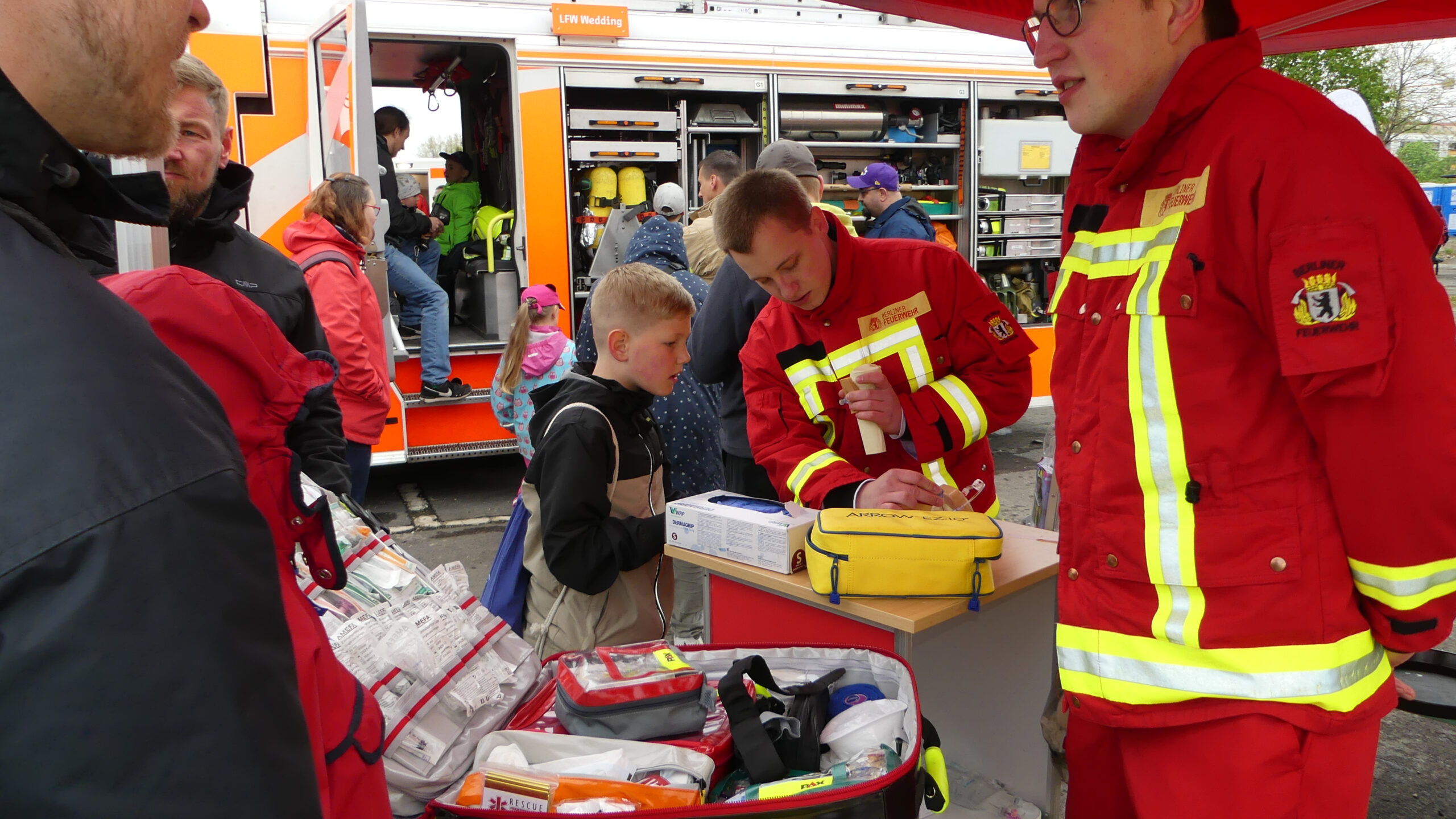 Feuerwehrmann zeigt einem Kind einen Rettungskoffer
