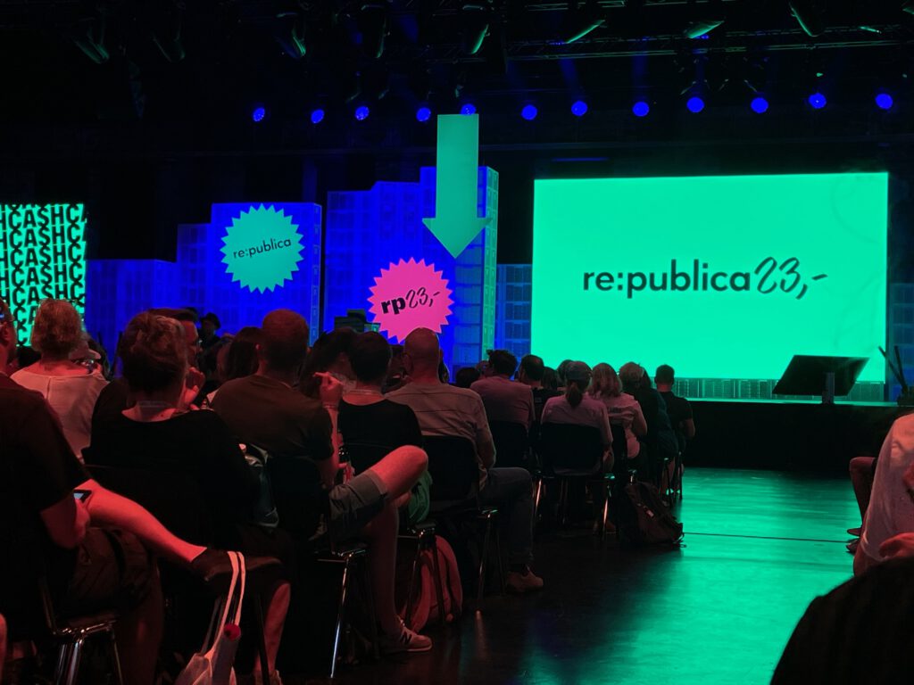 Auf der Bühne ist eine Grüne projezierte Fläche mit der Aufschrift republica 23 zu sehen