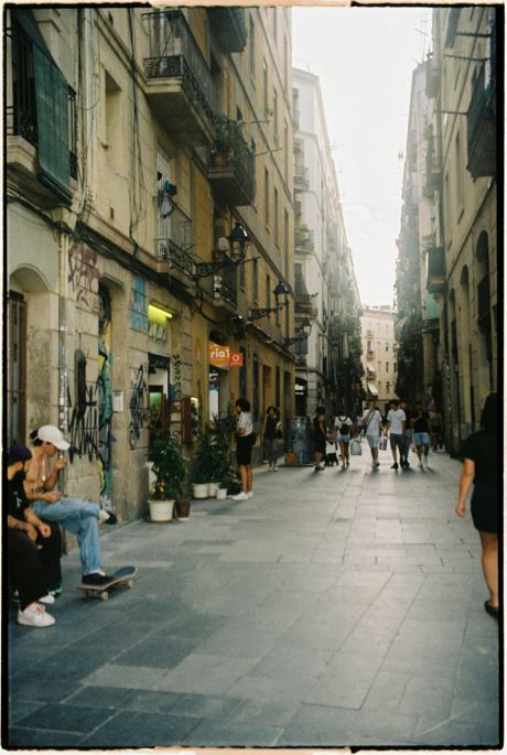 Menschen schlendern durch eine Altstadt-Gasse in Barcelona.