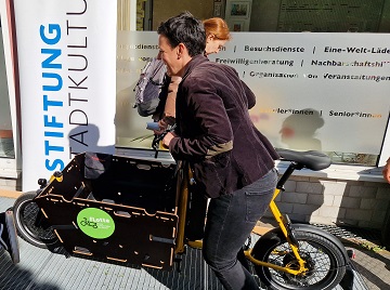 Eine Frau fährt mit einem Lastenrad die Rampe zum Eingang der oskar freiwilligenagentur noch.