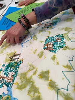Eine Hand zeigt etwas auf einem gemalten Stadtplan.