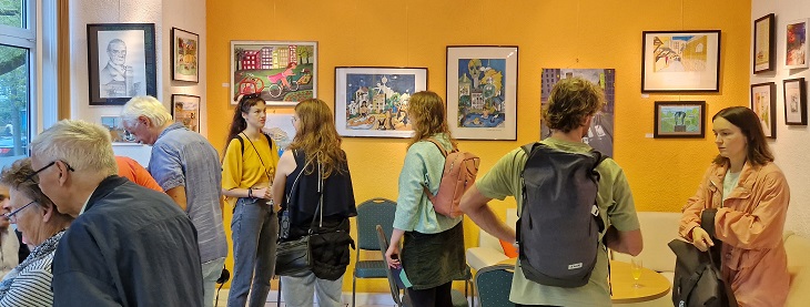 Besucher:innen bei der Vernissage sehen sich die Bilder in der Ausstellung an.