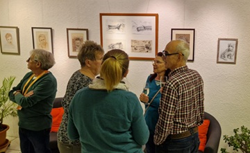 Eine Gruppe von vier Personen steht bei der Vernissage von "Die Natur in den Bildern" zusammen und unterhält sich. Im Hintergrund sieht man Kunstwerke an einer Wand.