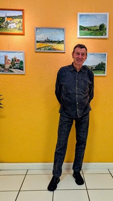 Der Künstler Gunther Rieger vor einigen seiner Landschaftsbilder in der oskar galerie.