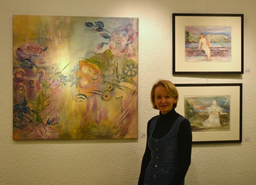 Die Künstlerin Petra Seirig steht vor drei ihrer Bilder.