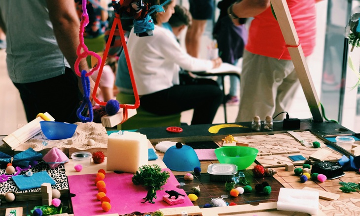 Ein Tisch voller Upcycling-Materialien und im Hintergrund Kinder.