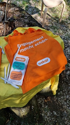 Stifte, Flyer und Beutel von der oskar Freiwilligenagentur. Auf den orangenen Beuteln steht: Engagement macht schön.