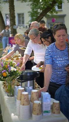 Geburtstagsgäste stehen am Buffet und bedienen sich an Snacks und Kaffee.