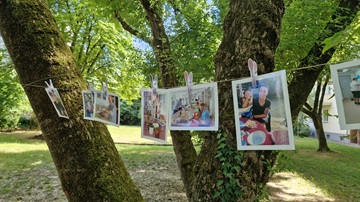 Fotos hängen nebeneinander an einer Leine, die zwischen Bäumen gespannt ist.
