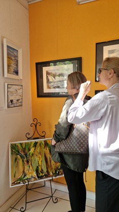 Zwei Frauen schauen sich Bilder an einer Wand an.
