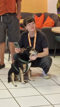 Ein Hund und sein Frauchen sitzen auf dem Boden in der Ausstellung.
