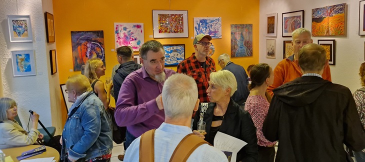 Besucher der Vernissage stehen in der Ausstellung und unterhalten sich.